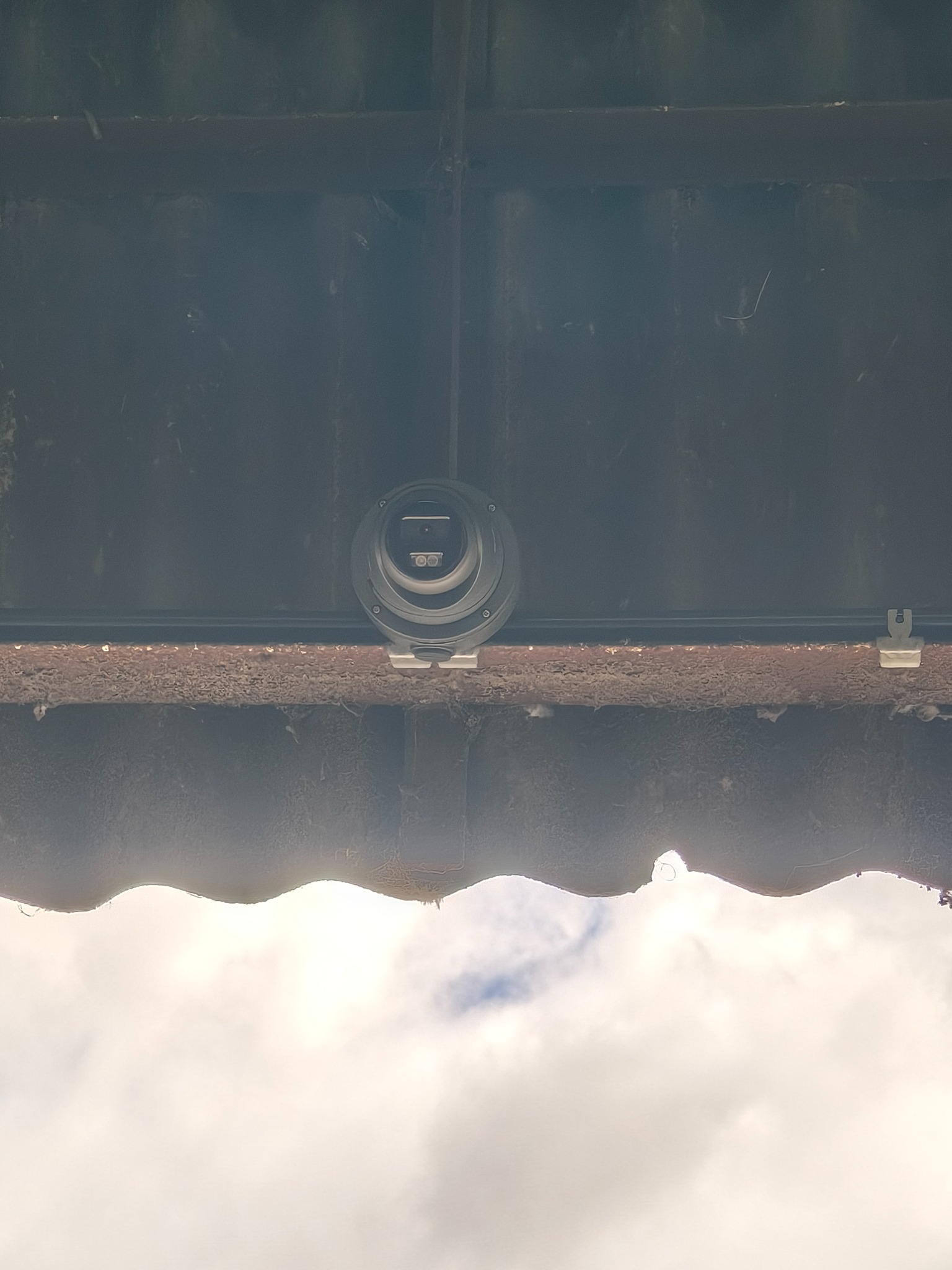 Circular CCTV camera mounted high under a roof
