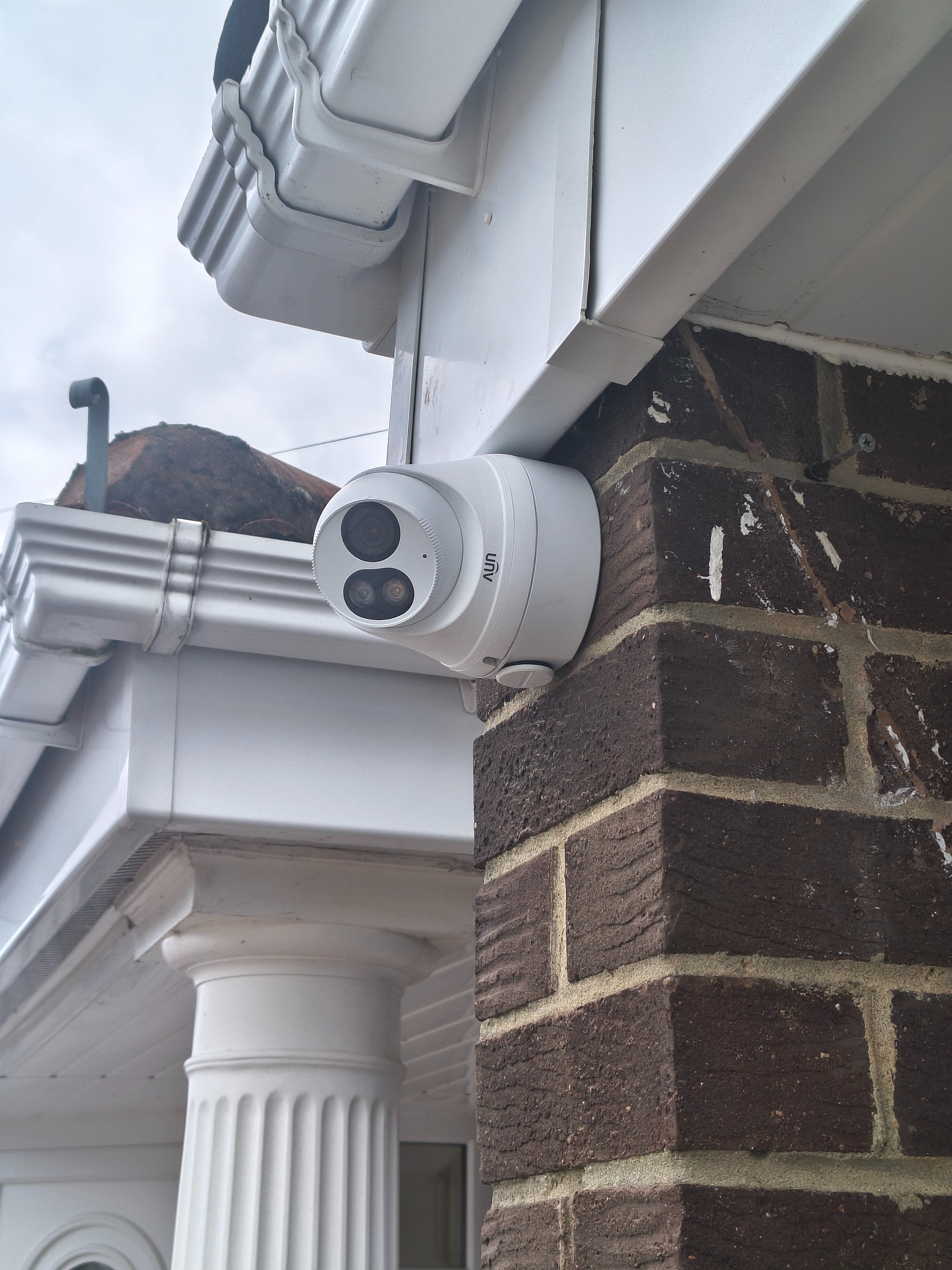 Turret CCTV camera fitted beneath the eaves of a brick building